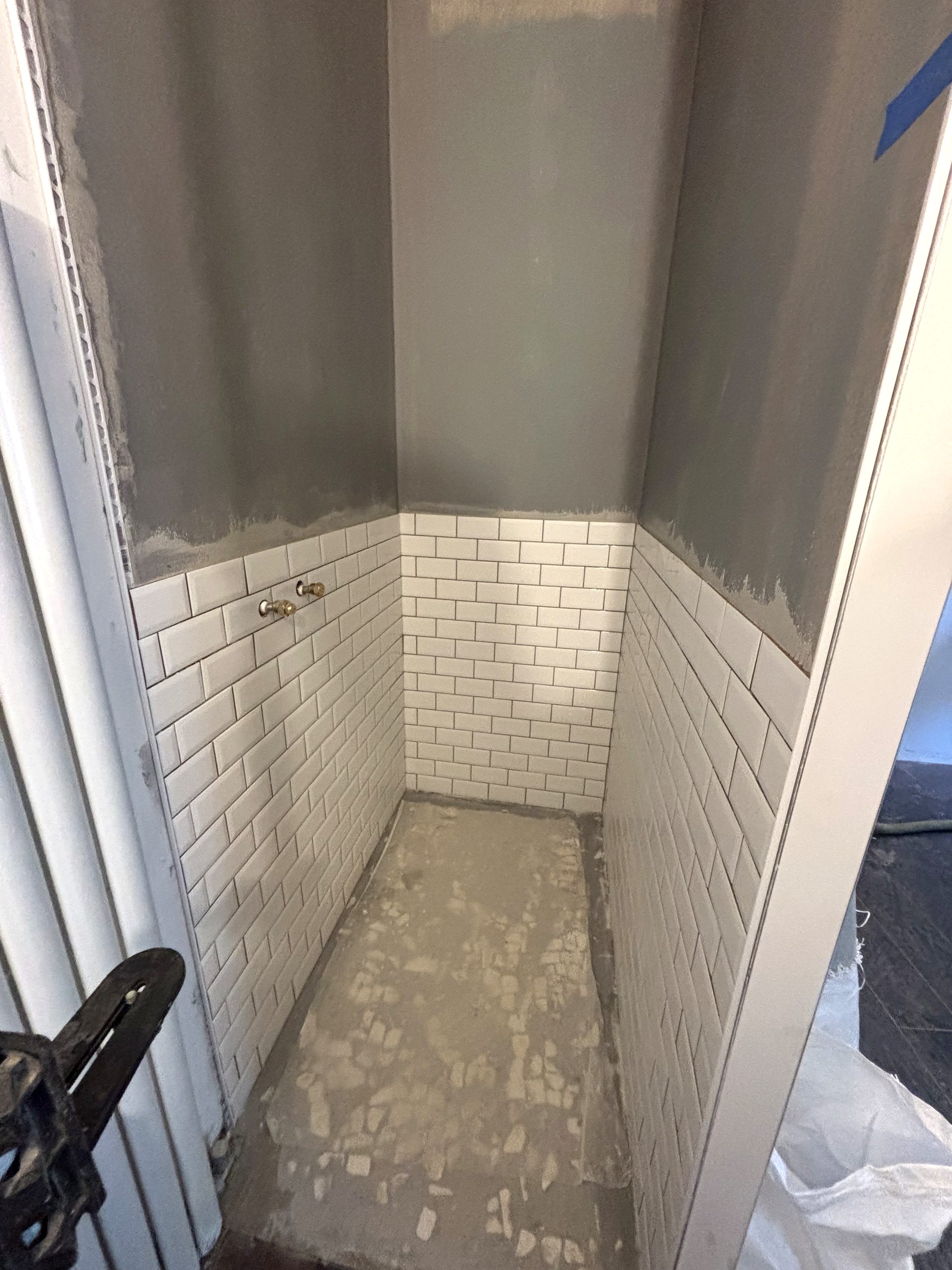 faience_douche Cuisine en L sur mesure avec façades vert mat et bois, plan de travail clair, rangements intégrés et électroménager encastré, réalisée par FAKT Agencement